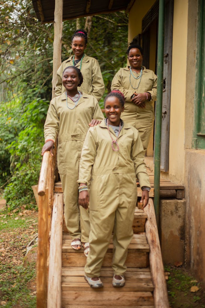 Four women in similar uniforms smiling on a wooden porch with greenery.